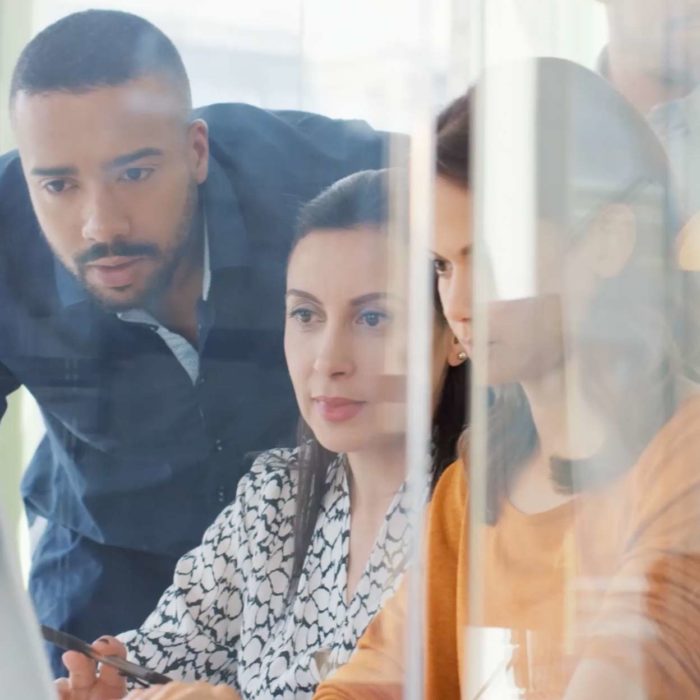 Three employees working together at computer.