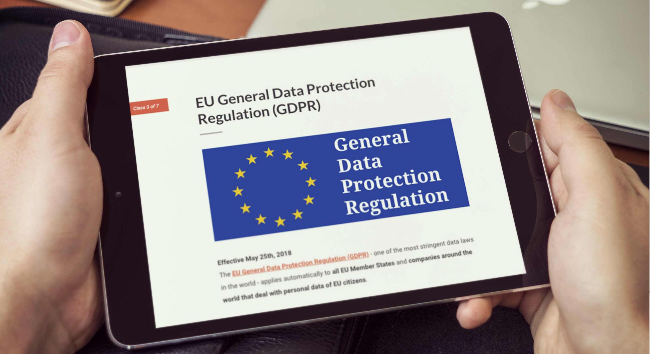 Hands holding tablet with a responsive elearning course page about the General Data Protection Regulation